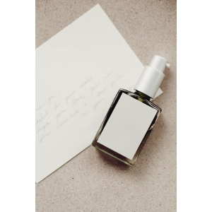 a bottle of perfume sitting next to a piece of paper