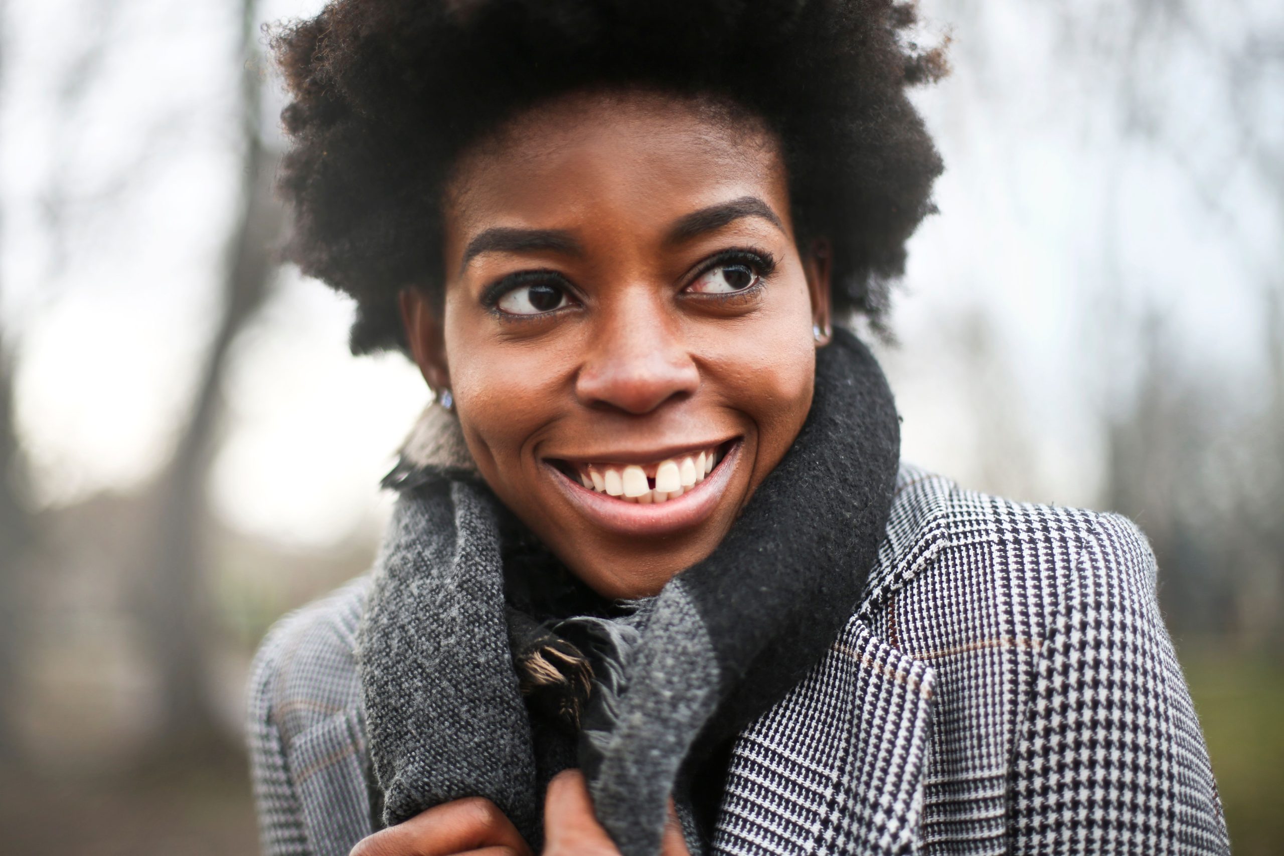 Portrait of a smiling woman in a scarf outdoors during autumn in Budapest.